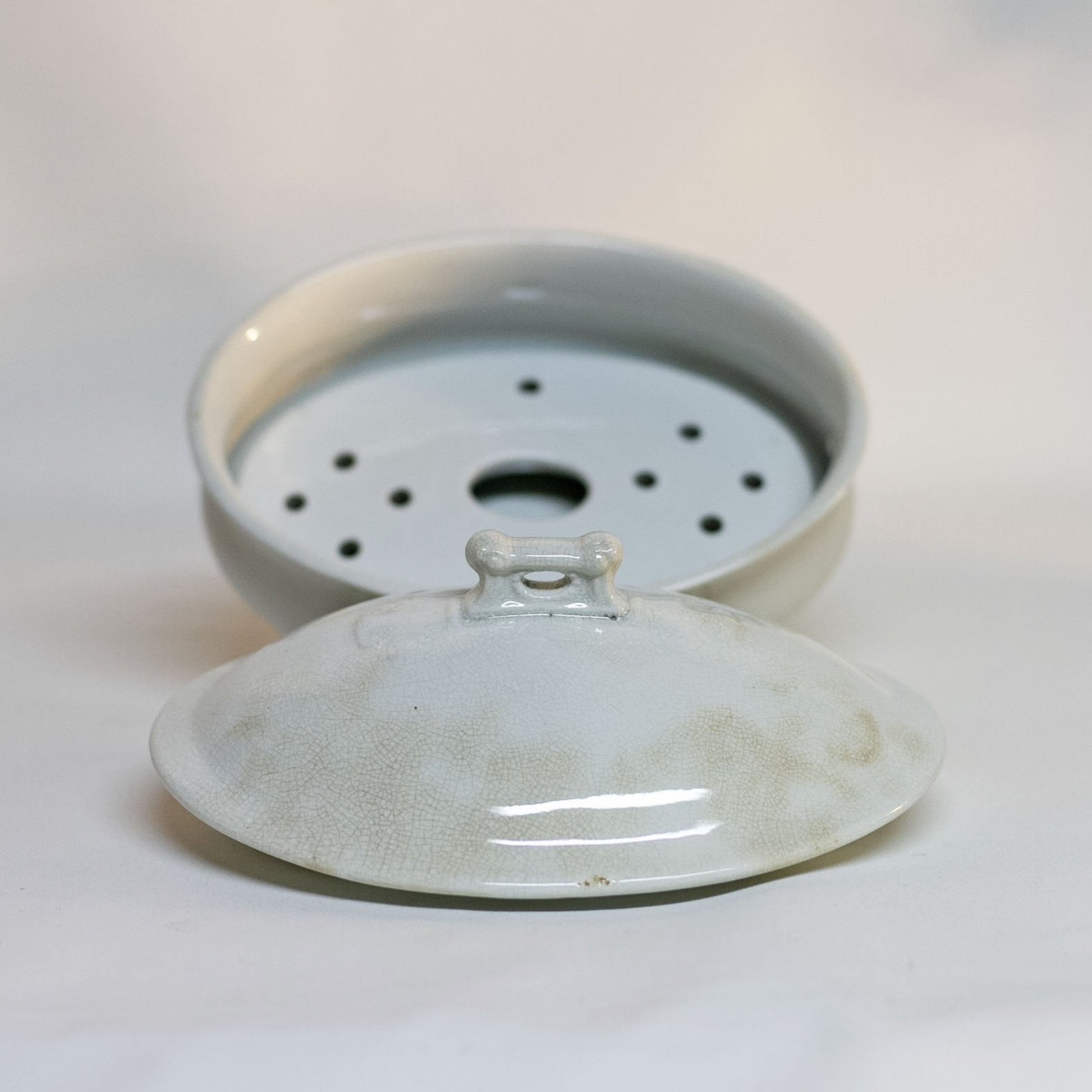 Gorgeous white antique IRONSTONE THREE-PIECE SOAP DISH made by MELLOR, TAYLOR AND COMPANY of Burslem Stoke-on-Tent in England. Set is in the shape of a small oval tureen and complete, including the drain and lid. Stamped dating the piece to between 1880-1904. Some staining, no chips.