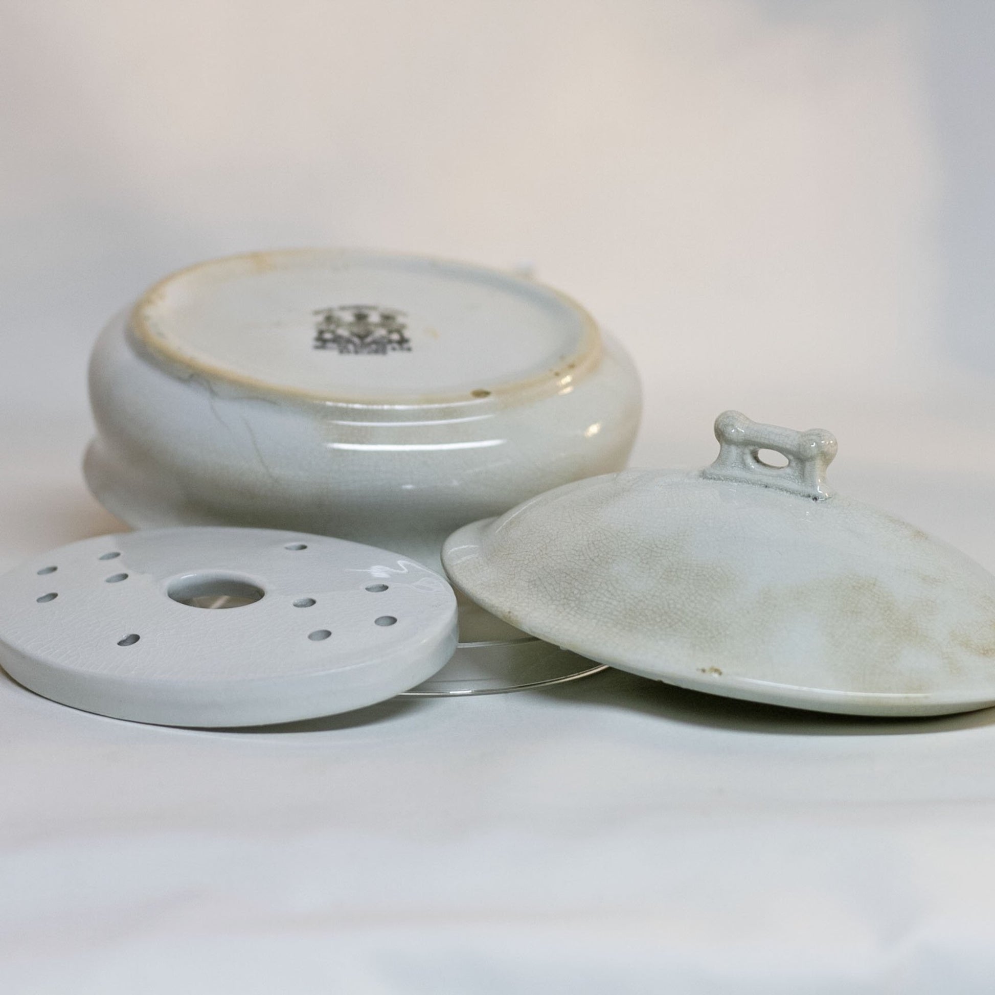 Gorgeous white antique IRONSTONE THREE-PIECE SOAP DISH made by MELLOR, TAYLOR AND COMPANY of Burslem Stoke-on-Tent in England. Set is in the shape of a small oval tureen and complete, including the drain and lid. Stamped dating the piece to between 1880-1904. Some staining, no chips.