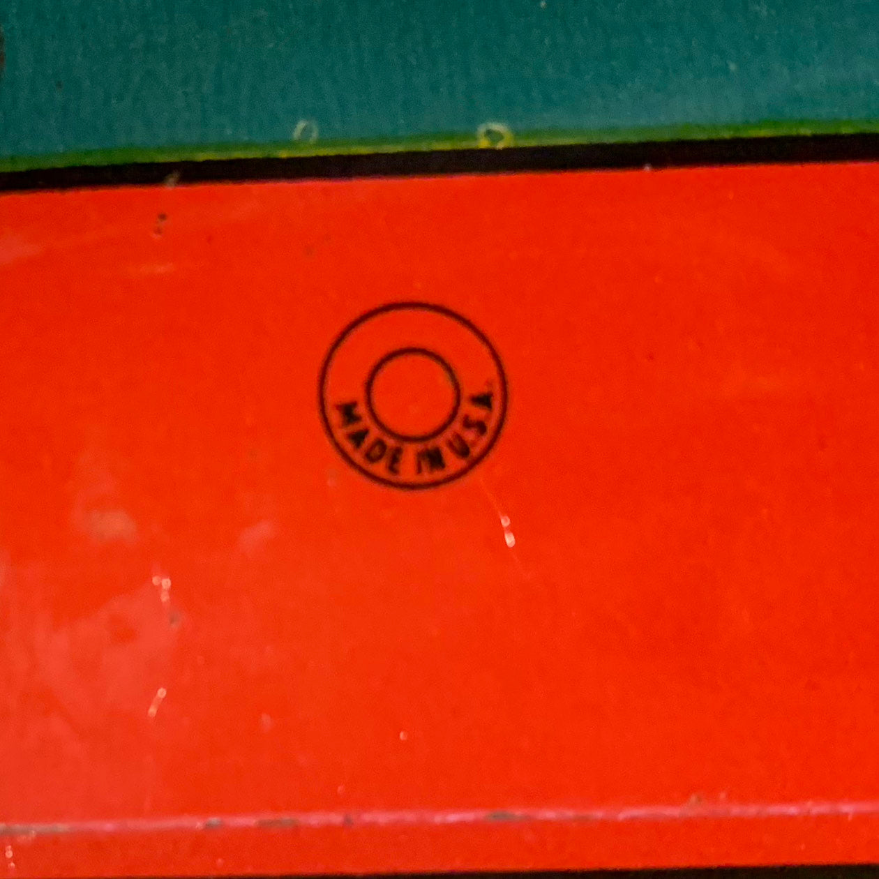 This is an older style tin LITHOGRAPH CLOWN NOISEMAKER that likely dates to the 1930s or 1940s is in the shape of a small can. The lithograph depicts two clowns, one dressed in a white and red polka-dot clown suit and the other is "toothless" and dressed in blue plaid. Scene background in yellow. A red wooden handle is