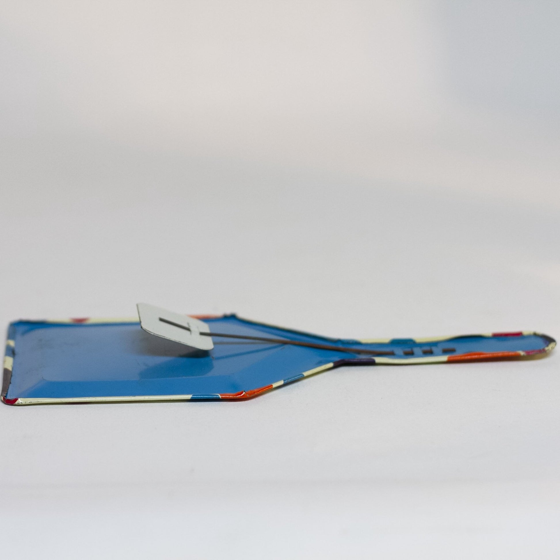 TIN-LITHOGRAPH POLKA DOT CLACKER 1950s NOISEMAKER. The lithograph on the shovel shaped noisemaker is filled with red, orange, purple, and blue polka dots. Appears to be a style that was part of a Party Time set made by the U.S. Metal Toy Manufacturing Company of Brooklyn, New York, but the lithograph is not marked.