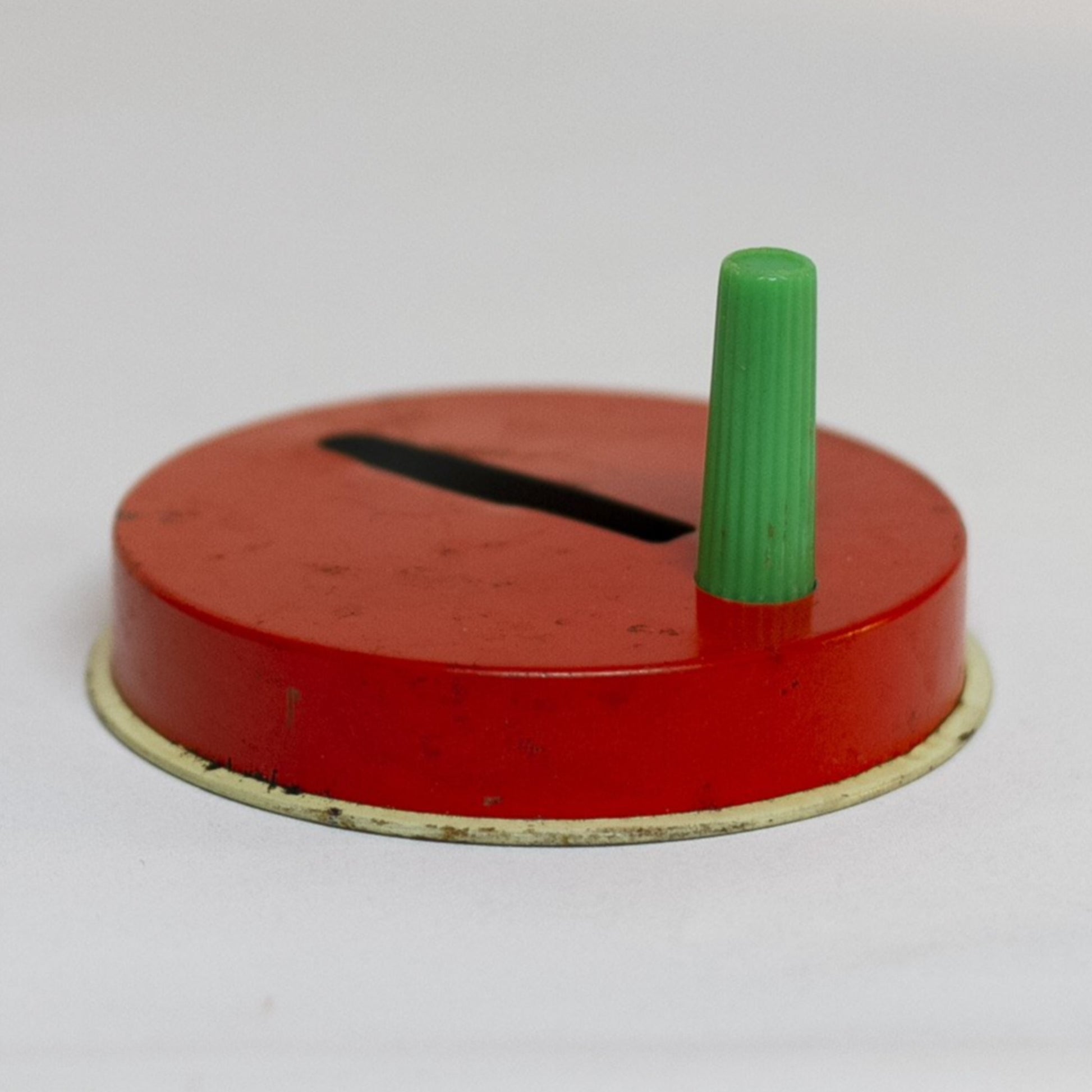 This round TIN-LITHOGRAPH RATCHET-STYLE NEW YEARS EVE NOISEMAKER made by US Metal Toys from the late 1940s to 1950s depicts a couple, a man dressed in a top hat and tailcoat and a woman in cha-cha costume dancing. The light-colored background is filled with red and blue balloons and ribbon streamers.
