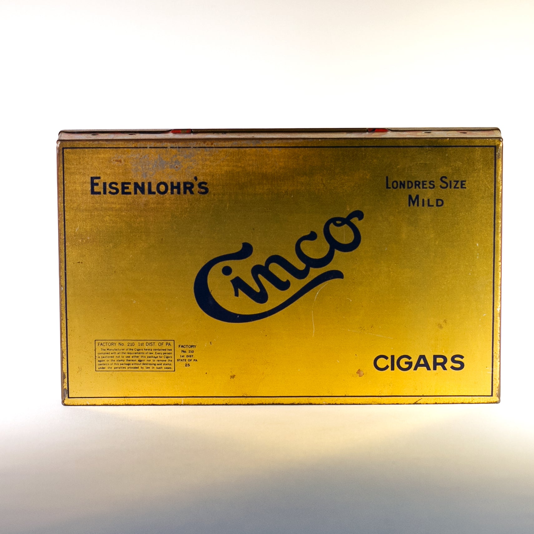EISENLOHR'S CINCO CIGARS TIN is from the 1920s. Cinco was the chief product of the Philadelphia based cigar firm of Otto Eisenlohr and Brothers, a popular priced brand in the 1920s, producing and selling 210 million of the cigars. The brand was considered the largest individual seller of cigars in the United States. 