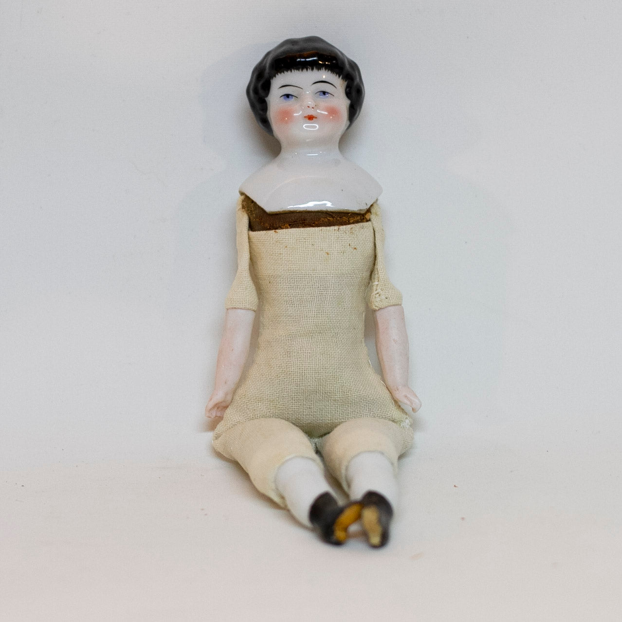 Antique CHINA SHOULDER DOLL HEAD DOLL 7 ¾” long; shoulder head measures 2" tall by 1 ⅝" wide at shoulders. Blue eyes, rosy cheeks, closed mouth and molded black curly hair with straight cut bangs. Bisque arms and legs, hand-sewn clean muslim body; stuffing appears original. No fractures. Likely German circa 1900. 