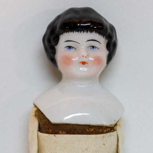 Antique CHINA SHOULDER DOLL HEAD DOLL 7 ¾” long; shoulder head measures 2" tall by 1 ⅝" wide at shoulders. Blue eyes, rosy cheeks, closed mouth and molded black curly hair with straight cut bangs. Bisque arms and legs, hand-sewn clean muslim body; stuffing appears original. No fractures. Likely German circa 1900. 
