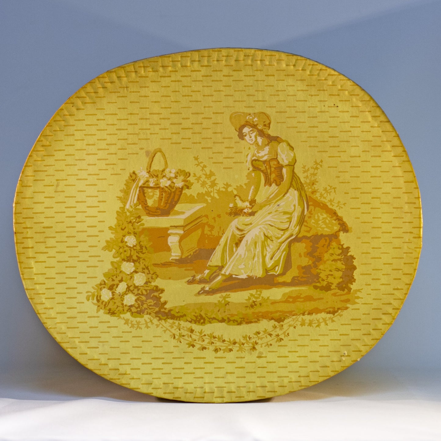 Reproduction of a "BRIDE'S BOX" made from slightly oval shaped large hat box covered in vintage yellow wallpaper featuring lambs and a Colonial girl. Inside and bottom papered with pages from the Maine Antique Digest, September 1977. Measures about 10" high by 15" in length by 13" wide.