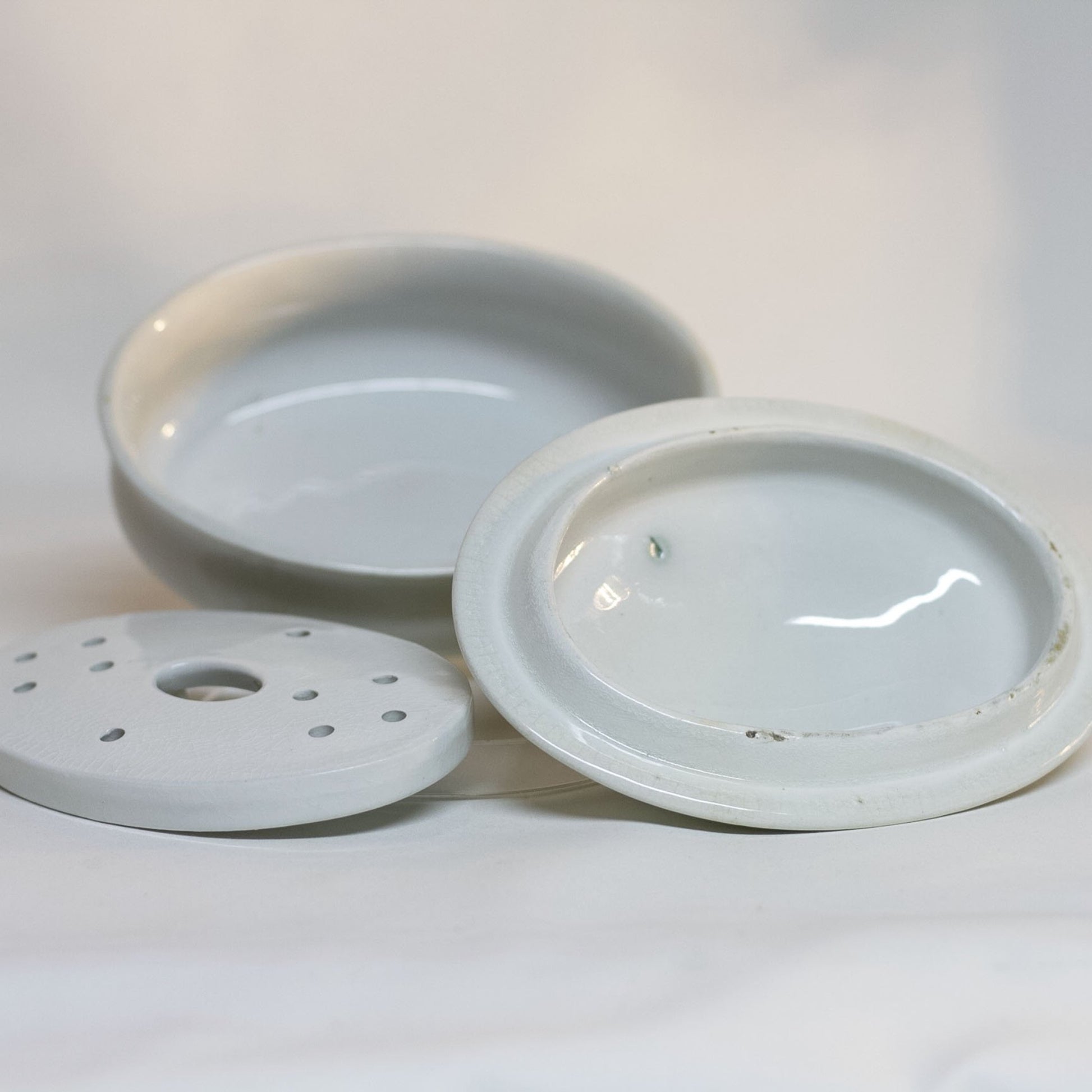 Gorgeous white antique IRONSTONE THREE-PIECE SOAP DISH made by MELLOR, TAYLOR AND COMPANY of Burslem Stoke-on-Tent in England. Set is in the shape of a small oval tureen and complete, including the drain and lid. Stamped dating the piece to between 1880-1904. Some staining, no chips.